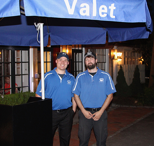 Valet station with 2 valets smiling at camera